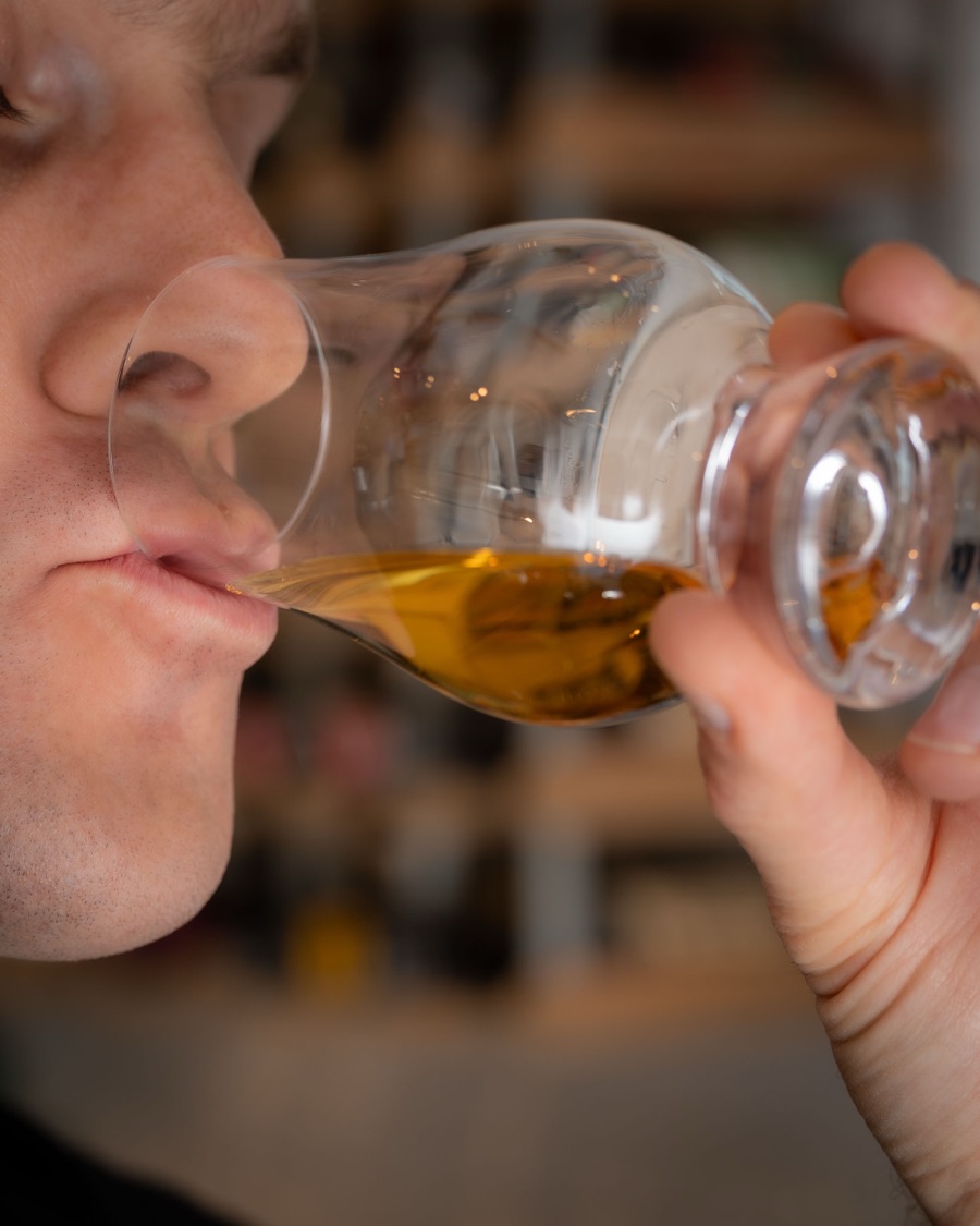 Taking a sip of whisky from a Glencairn glass