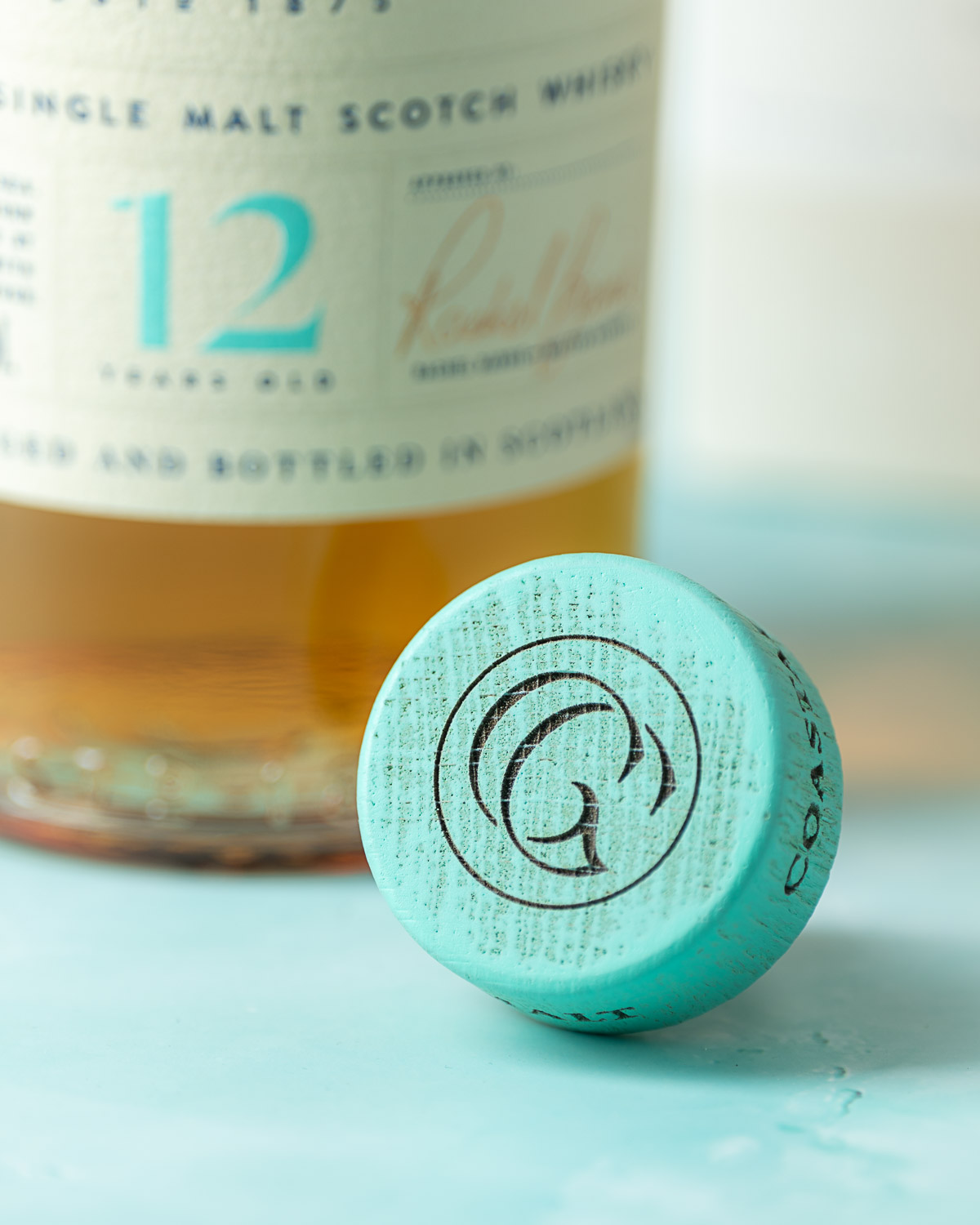 Close-up of the stopper's embossed monogram with the bottle blurred behind it